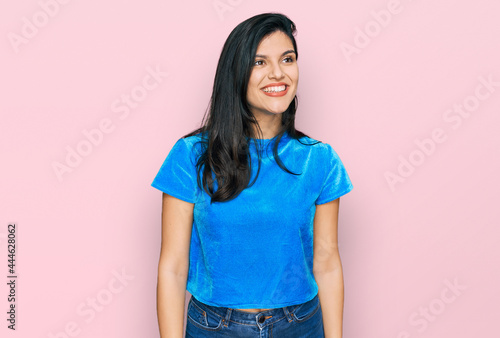 Young hispanic woman wearing casual clothes looking away to side with smile on face, natural expression. laughing confident.