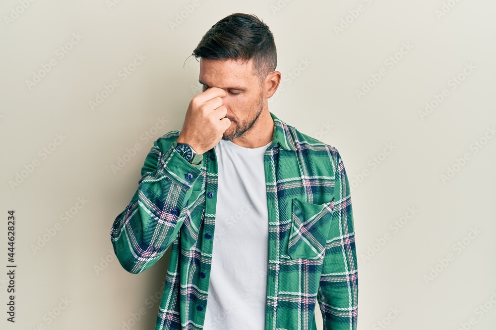 Handsome man with beard wearing casual clothes tired rubbing nose and eyes feeling fatigue and headache. stress and frustration concept. Handsome man with beard wearing casual clothes tired rubbing nose and eyes feeling fatigue and headache. stress and frustration concept.