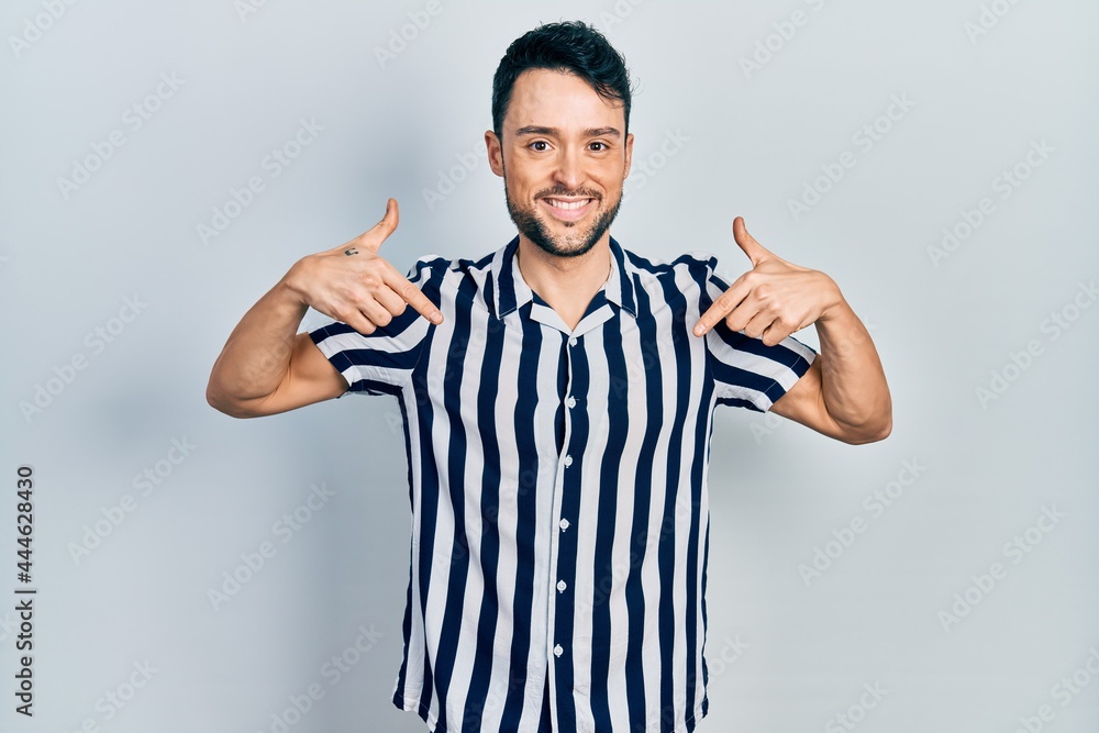 Fototapeta premium Young hispanic man wearing casual clothes looking confident with smile on face, pointing oneself with fingers proud and happy.