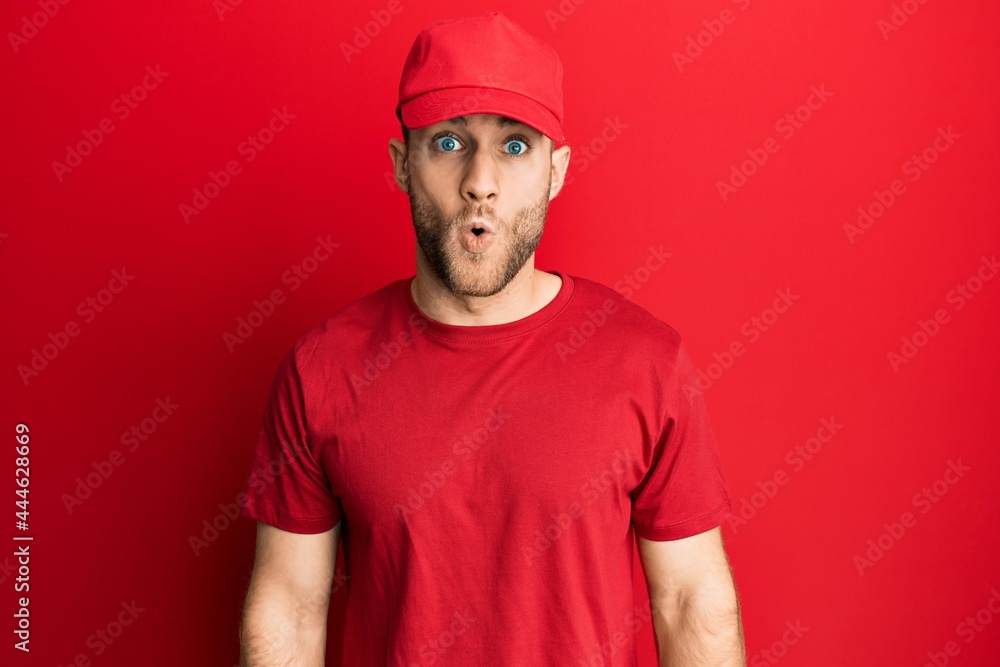 Young caucasian man wearing delivery uniform and cap scared and amazed with open mouth for surprise, disbelief face Young caucasian man wearing delivery uniform and cap scared and amazed with open mouth for surprise, disbelief face