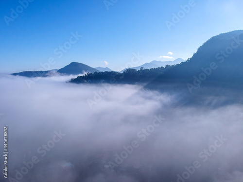 Aerial view of Itaipava  Petr  polis. Early morning with a lot of fog in the city. Mountains with blue sky and clouds around Petr  polis  mountainous region of Rio de Janeiro  Brazil. Drone photo.  