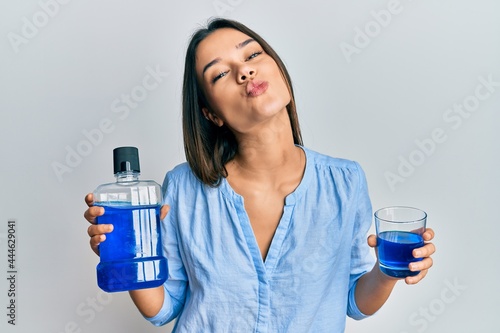 Bild auf Leinwand Young hispanic girl holding mouthwash for fresh breath looking at the camera blowing a kiss being lovely and sexy