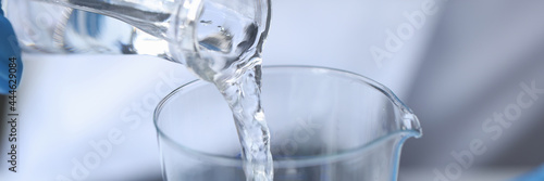 Clear liquid is poured from glass bottle photo