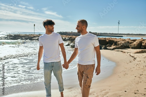 Young gay couple smiling happy walking at the beach.