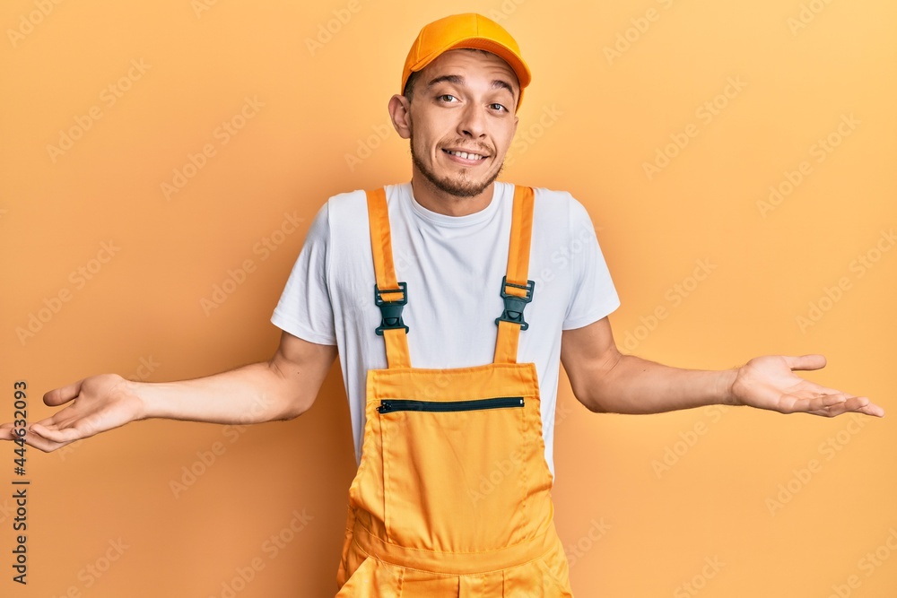 Hispanic young man wearing handyman uniform smiling showing both hands open palms, presenting and advertising comparison and balance