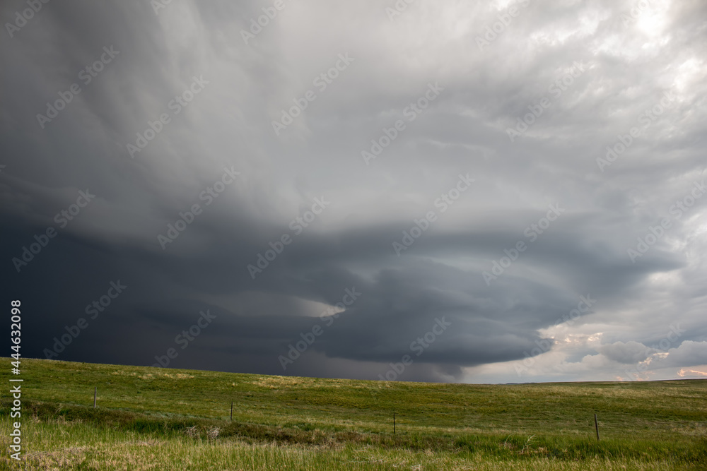 An anticyclonic supercell thunderstorm hangs in the sky over the high plains, its updraft spinning with a striated appearance.