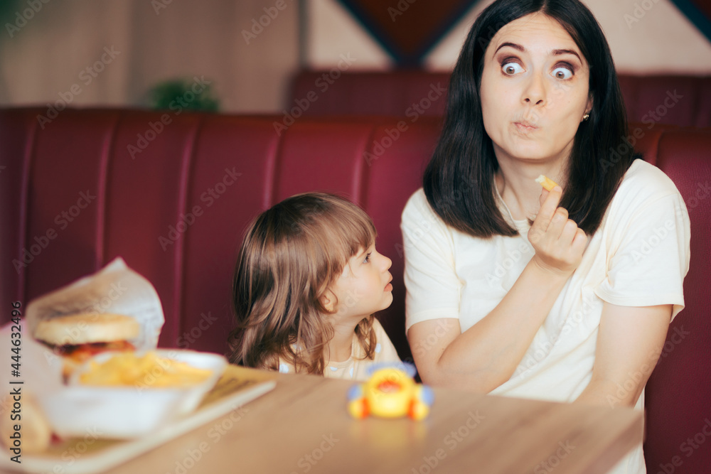 Funny Mom Having French Fries in front of her Toddler Daughter