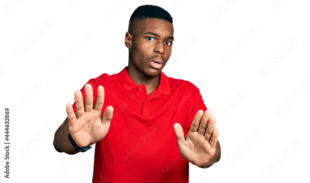 Young african american man wearing casual red t shirt moving away hands palms showing refusal and denial with afraid and disgusting expression. stop and forbidden. Young african american man wearing casual red t shirt moving away hands palms showing refusal and denial with afraid and disgusting expression. stop and forbidden.