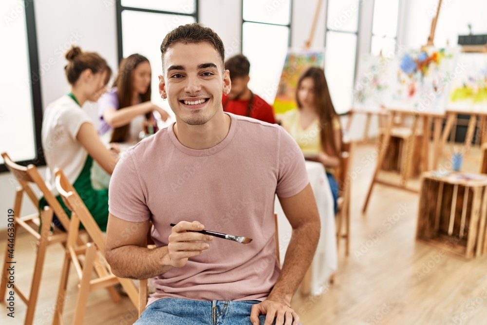 Group of people drawing sitting on the table. Young man smiling happy looking to the camera at art studio. Group of people drawing sitting on the table. Young man smiling happy looking to the camera at art studio.