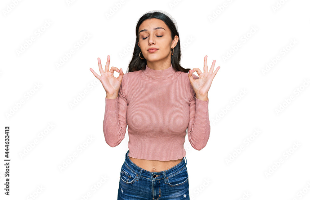 Young hispanic girl wearing casual clothes relax and smiling with eyes closed doing meditation gesture with fingers. yoga concept. Young hispanic girl wearing casual clothes relax and smiling with eyes closed doing meditation gesture with fingers. yoga concept.