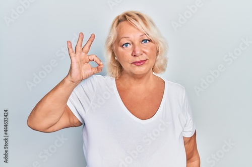 Wallpaper Mural Middle age blonde woman doing ok positive gesture relaxed with serious expression on face. simple and natural looking at the camera. Torontodigital.ca