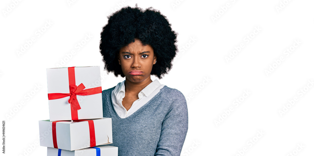 Young african american woman holding gifts skeptic and nervous, frowning upset because of problem. negative person. Young african american woman holding gifts skeptic and nervous, frowning upset because of problem. negative person.