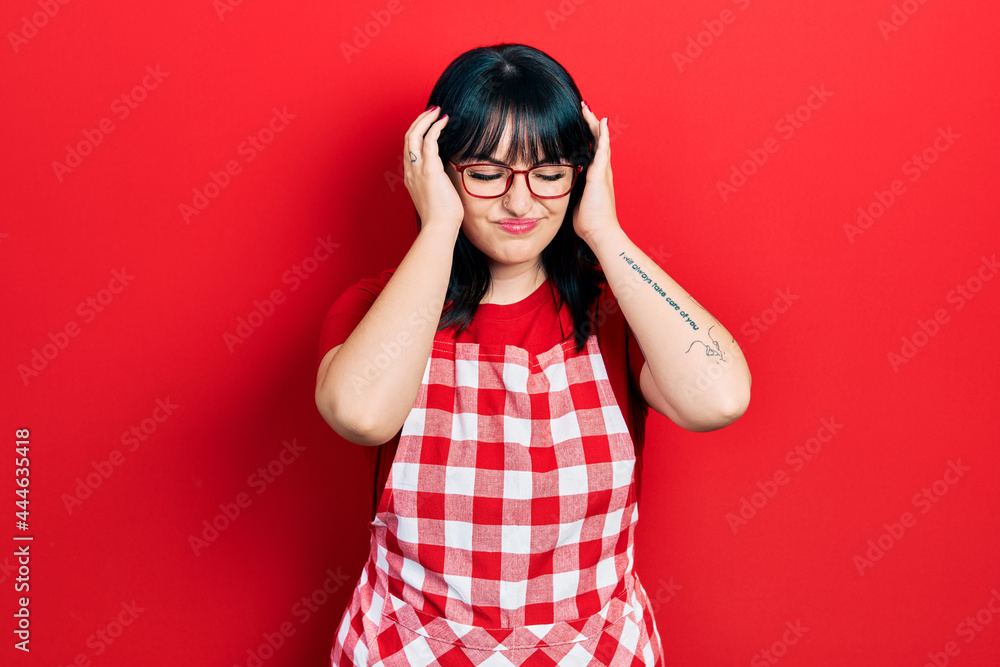 Young hispanic woman wearing cook apron and glasses suffering from headache desperate and stressed because pain and migraine. hands on head. Young hispanic woman wearing cook apron and glasses suffering from headache desperate and stressed because pain and migraine. hands on head.