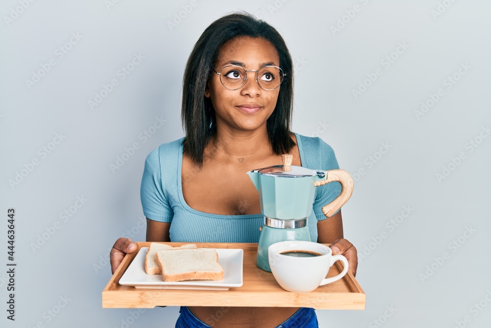 Young african american girl holding tray with breakfast food smiling looking to the side and staring away thinking. Young african american girl holding tray with breakfast food smiling looking to the side and staring away thinking.