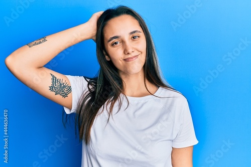Young hispanic woman wearing casual white t shirt confuse and wonder about question. uncertain with doubt, thinking with hand on head. pensive concept.