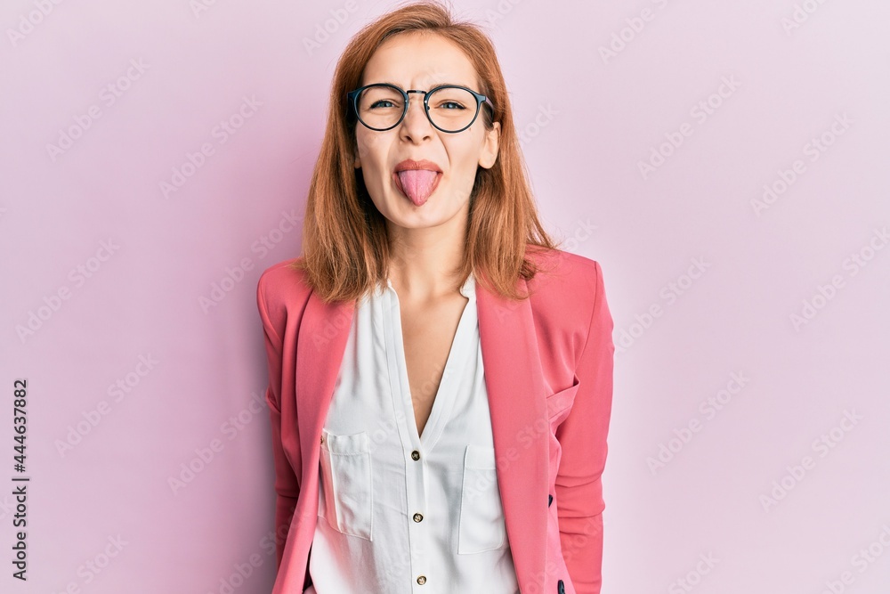 Young caucasian woman wearing business style and glasses sticking tongue out happy with funny expression. emotion concept.