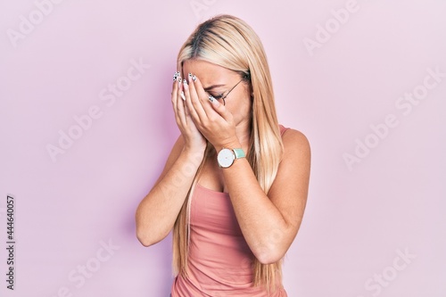 Young blonde girl wearing casual clothes with sad expression covering face with hands while crying. depression concept.