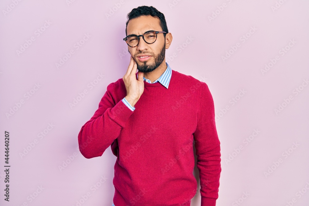 Hispanic man with beard wearing business shirt and glasses touching mouth with hand with painful expression because of toothache or dental illness on teeth. dentist Hispanic man with beard wearing business shirt and glasses touching mouth with hand with painful expression because of toothache or dental illness on teeth. dentist