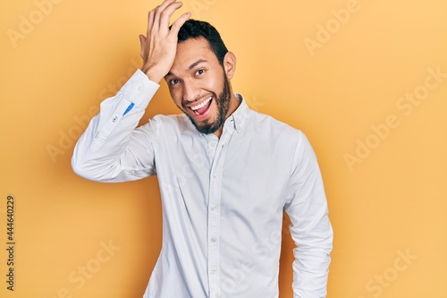 Hispanic man with beard wearing business shirt surprised with hand on head for mistake  remember error. forgot  bad memory concept.