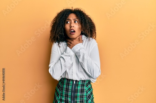 Beautiful african american woman with afro hair wearing scholar skirt shouting and suffocate because painful strangle. health problem. asphyxiate and suicide concept.