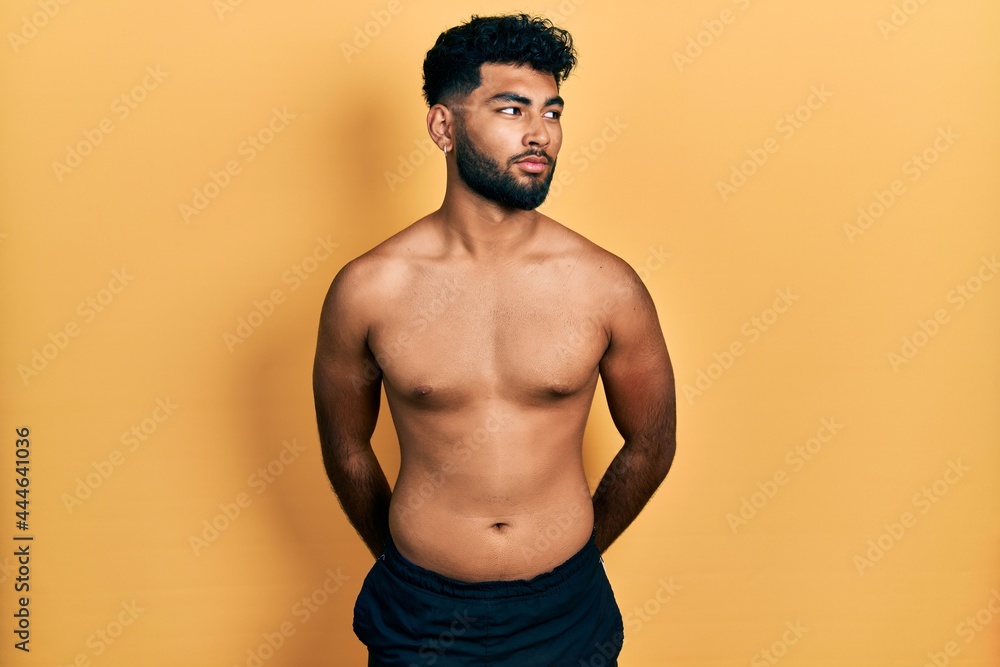 Arab man with beard wearing swimwear shirtless smiling looking to the