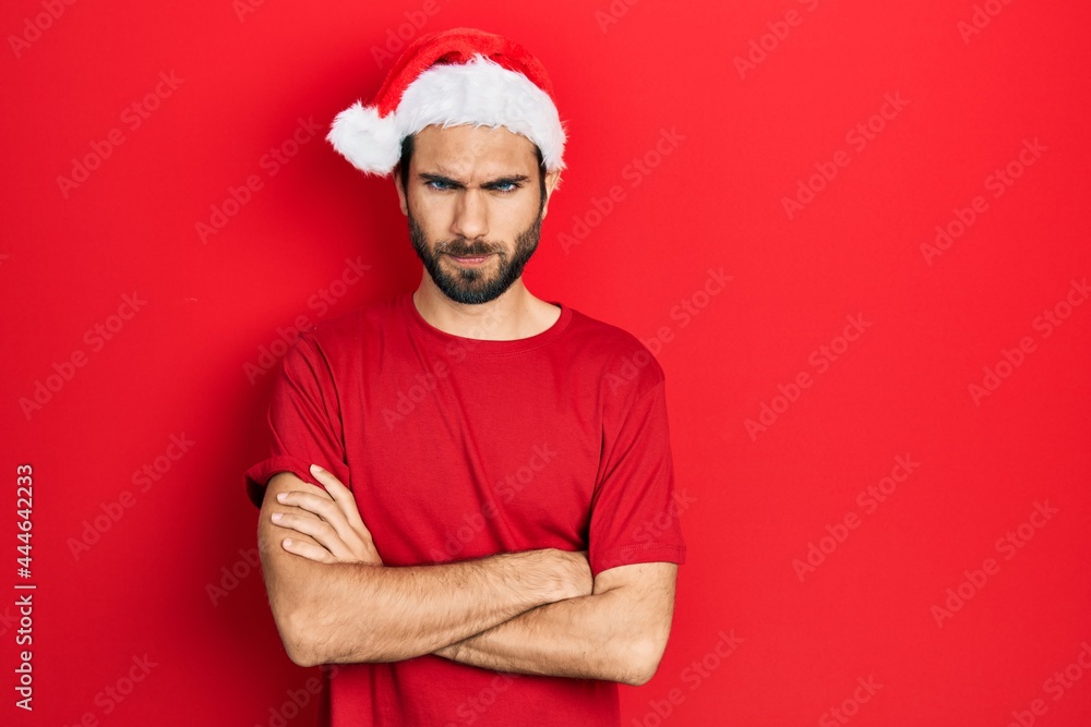 Fototapeta premium Young hispanic man wearing christmas hat skeptic and nervous, disapproving expression on face with crossed arms. negative person.