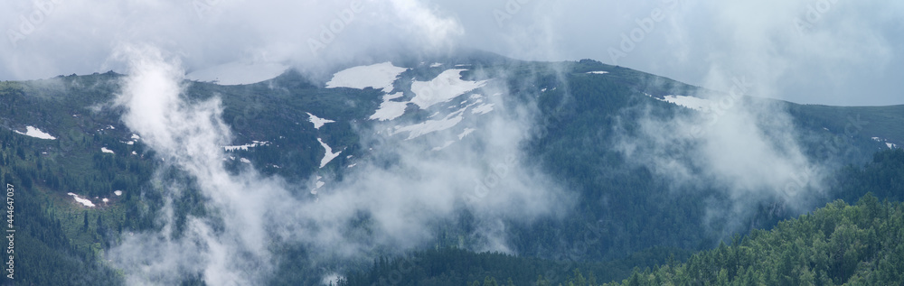 Mountain peaks in the clouds. Panoramic view.