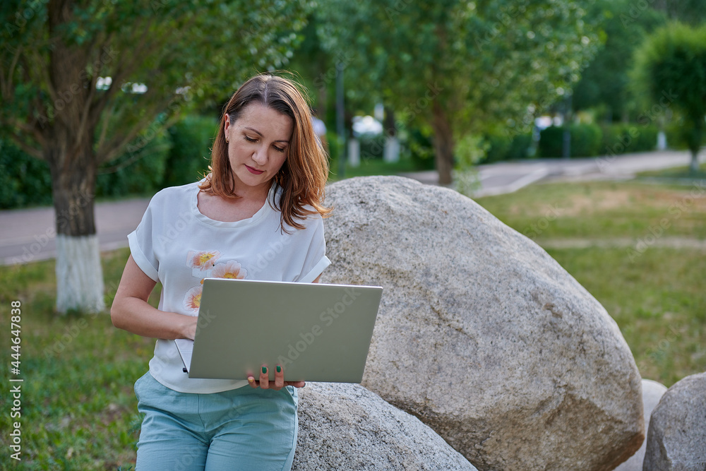 an interesting girl is sitting on a stone with a computer an interesting girl is sitting on a stone with a computer