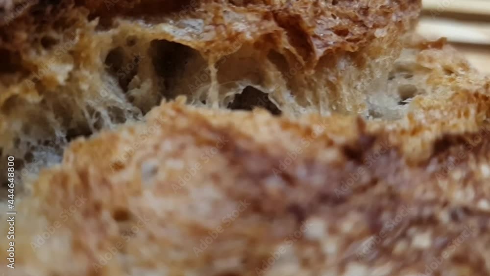 Closeup of delicious and crunchy bread crust. Review of a fresh loaf of bread. Beautifully golden baked bread made with sourdough on wooden table. Homemade sourdough crusty bread. Closeup of delicious and crunchy bread crust. Review of a fresh loaf of bread. Beautifully golden baked bread made with sourdough on wooden table. Homemade sourdough crusty bread.