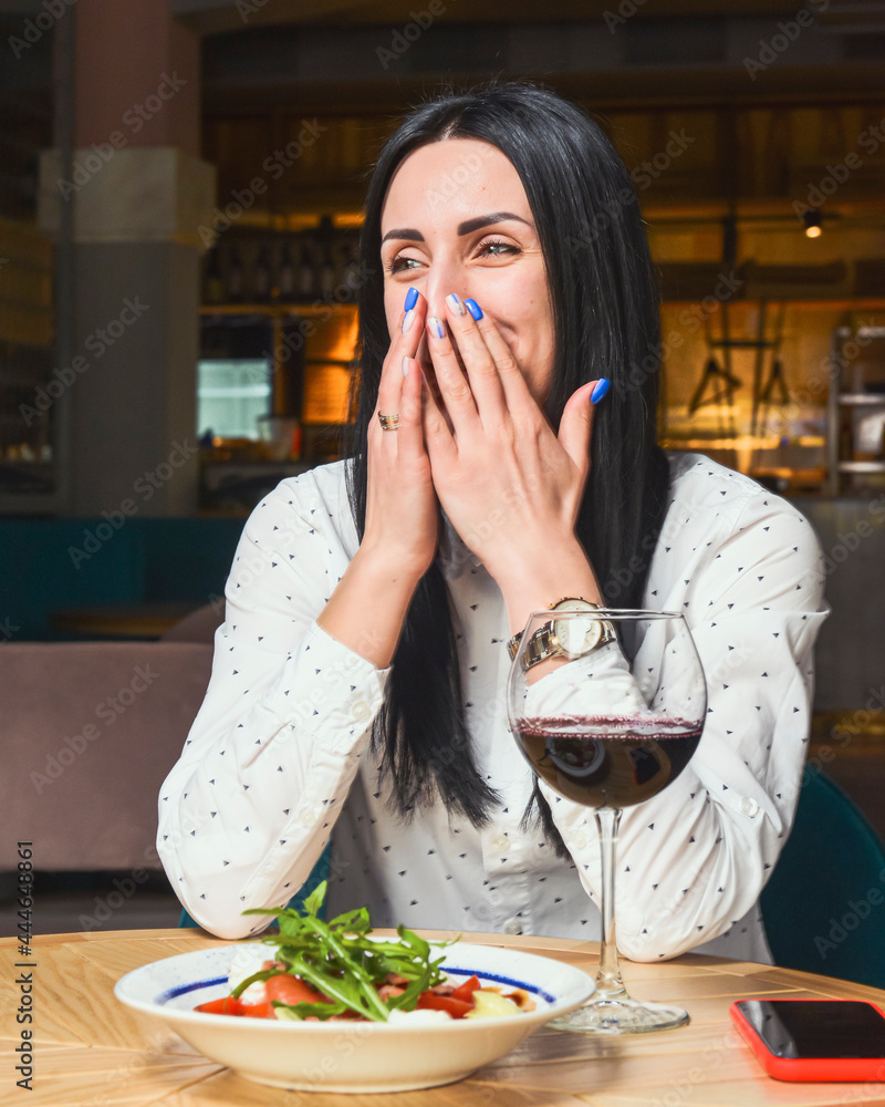 Young attractive woman having a healthy lunch in restaurant. Caucasian female with black hair dining.