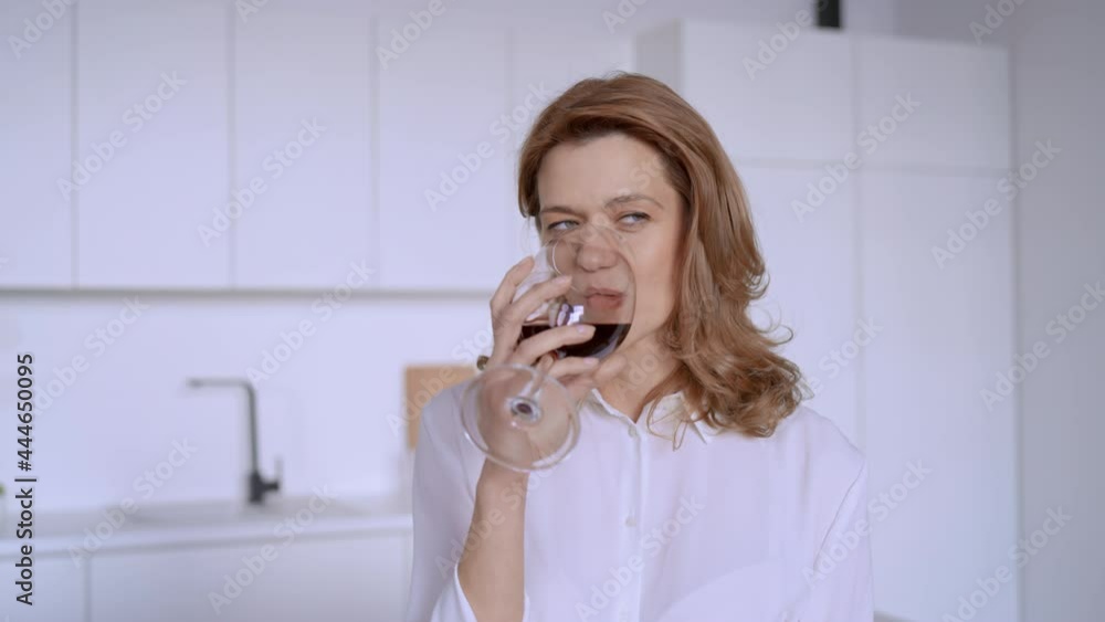 camera move slow motion adult caucasian woman holding glass with red wine enjoy drink at home kitchen with white interior camera move slow motion adult caucasian woman holding glass with red wine enjoy drink at home kitchen with white interior