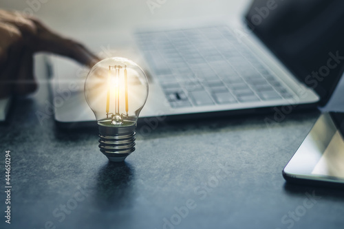 Bright light bulb with laptop and book. Business and education concept