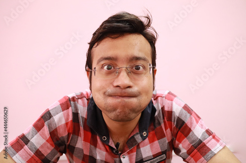 Fotografie Funny Indian man suppressing his laughter isolated on a pink background