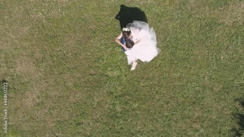 Top down aerial view of wedding couple spinning in a park on a background of grass. The groom took the bride in his arms. Bird eye top down view, slow motion 4k footage
