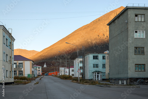 View of the street and buildings in the northern town. Mountain peaks illuminated at sunrise. An urban-type settlement in the Far North of Russia in the Arctic. Egvekinot, Chukotka, Siberia, Russia. photo