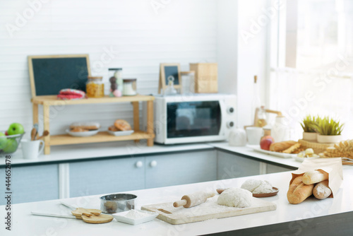 Modern kitchen with bread, dough bread and baking ingredients placed on table, sunlight shines from the window into the kitchen, food preparation concept