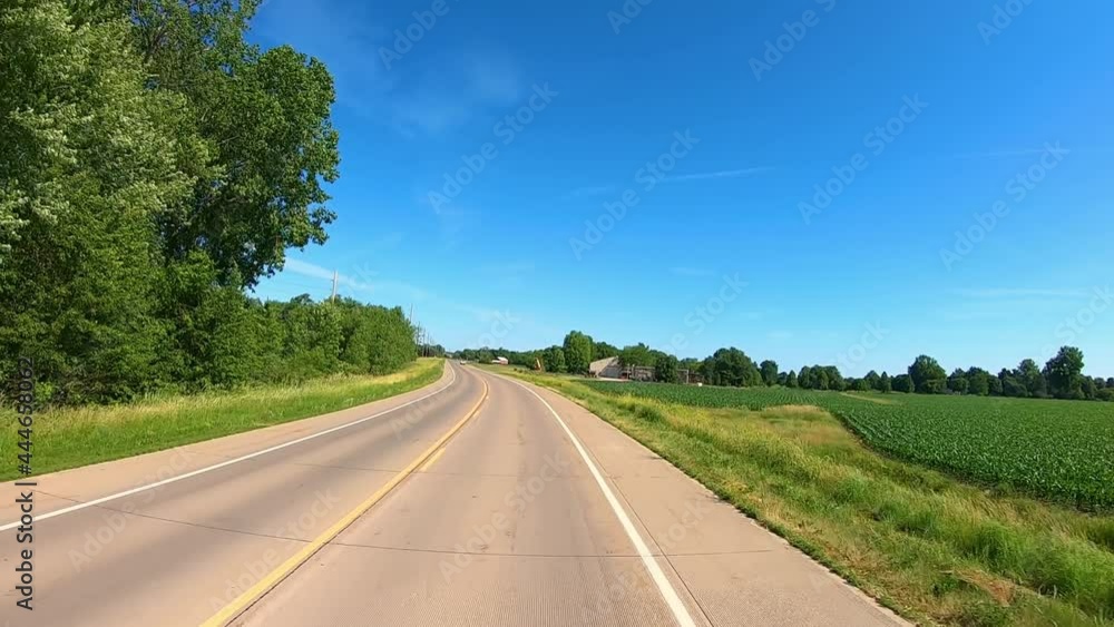 POV while driving on a rural county road past bikers and fields in rural Midwest on a late spring afternoon; concepts of agriculture, freedom and open road POV while driving on a rural county road past bikers and fields in rural Midwest on a late spring afternoon; concepts of agriculture, freedom and open road