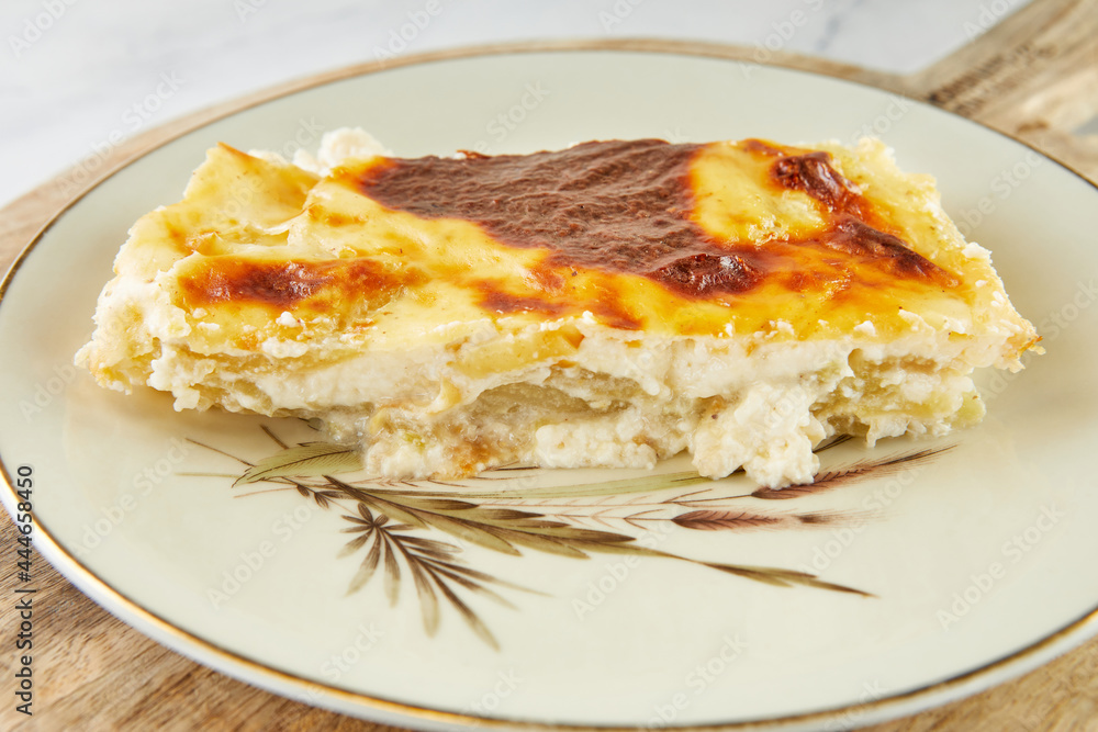 Casserole pie with cheese and sorrel on plate on light background