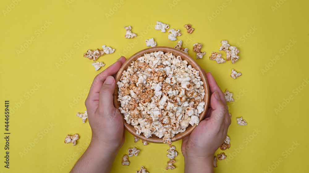Man holding a bowl of popcorn on yellow background. Man holding a bowl of popcorn on yellow background.