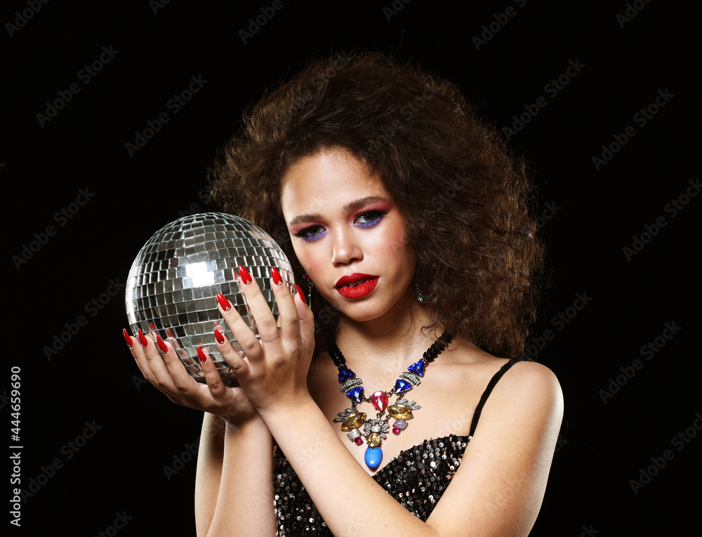 Naklejka premium Portrait of young beautiful african woman with creative make up holding disco balls over black background