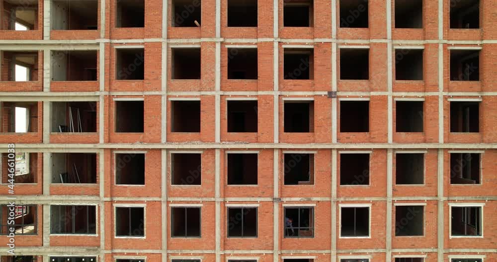 Unfinished brick building. Construction of a multi-storey building. The facade of the building is made of brick without windows during construction. Unfinished brick building. Construction of a multi-storey building. The facade of the building is made of brick without windows during construction.
