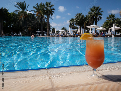 Glass of traditional Italian Aperol Spritz cocktail at the swimming pool