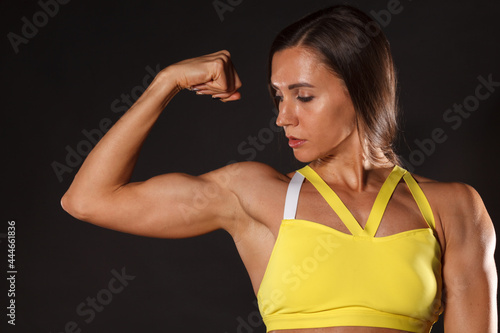female bodybuilder showing her biceps isolated on black background