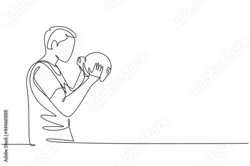 Single one line drawing handsome young male holding and kissing piggy bank. Wealth symbol and saving campaign concept for teenager. Modern continuous line draw design graphic vector illustration
