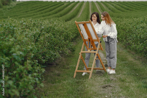 Elegant and beautiful girls painting in a field
