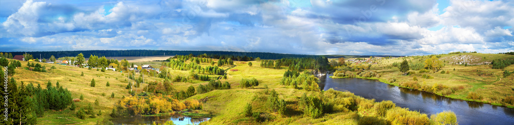 Picturesque horizontal sunny landscape with river, forest and meadows. Green natural background. A panoramic image of nature for use in design. Wallpaper.