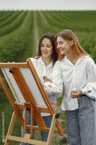 Elegant and beautiful girls painting in a field
