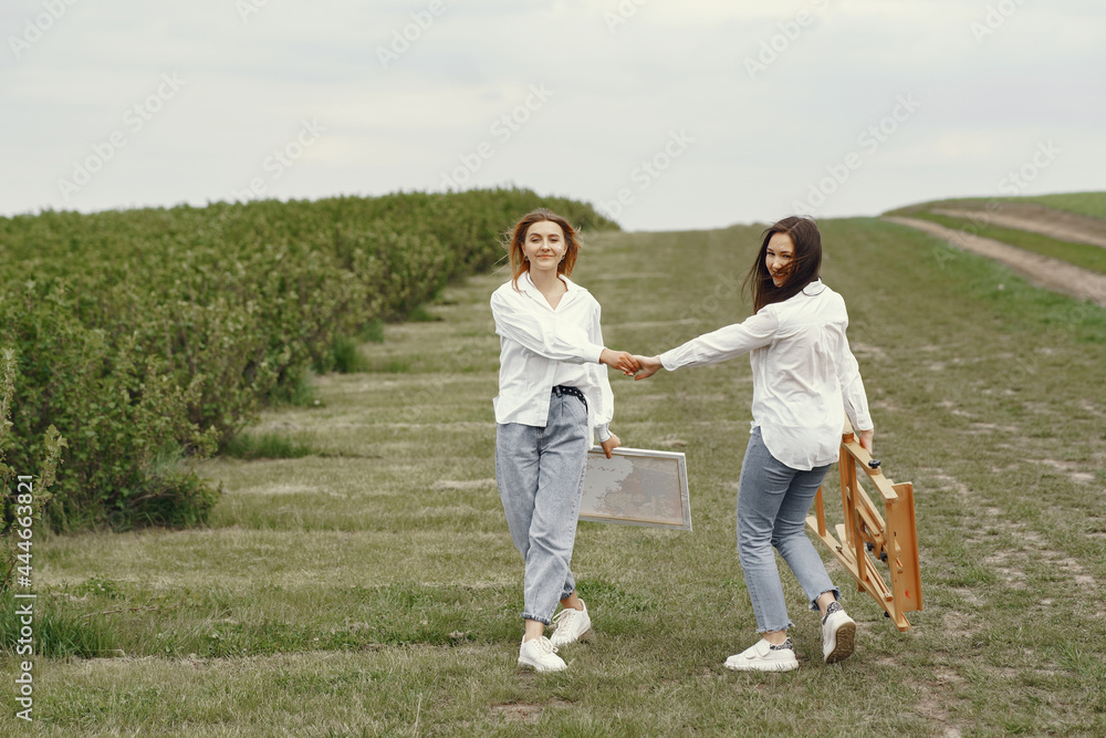Elegant and beautiful girls painting in a field Elegant and beautiful girls painting in a field