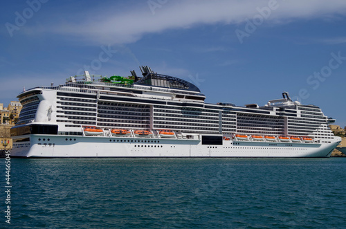 Gigantic MSC cruiseship cruise ship liner Grandiosa in port of Valletta, Malta with other maritime nautical vessels and city skyline on sunny summer day photo