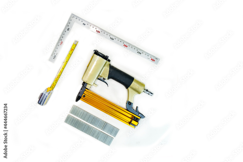 Pin nailer, tape measure and scene ruler on white background. Pin nailer, tape measure and scene ruler on white background.